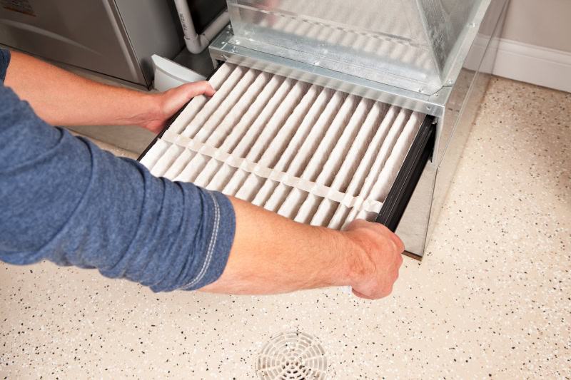 Male hands are installing a furnace air filter.